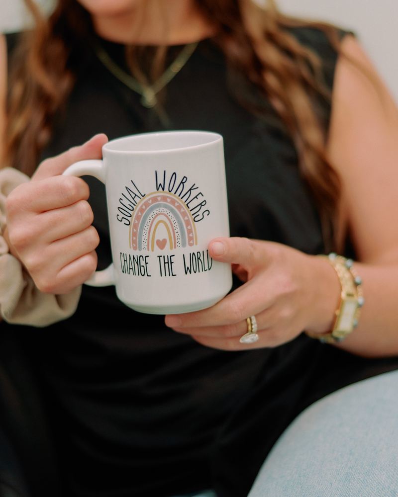 Jennifer holding a mug that reads “Social Workers Change the World”