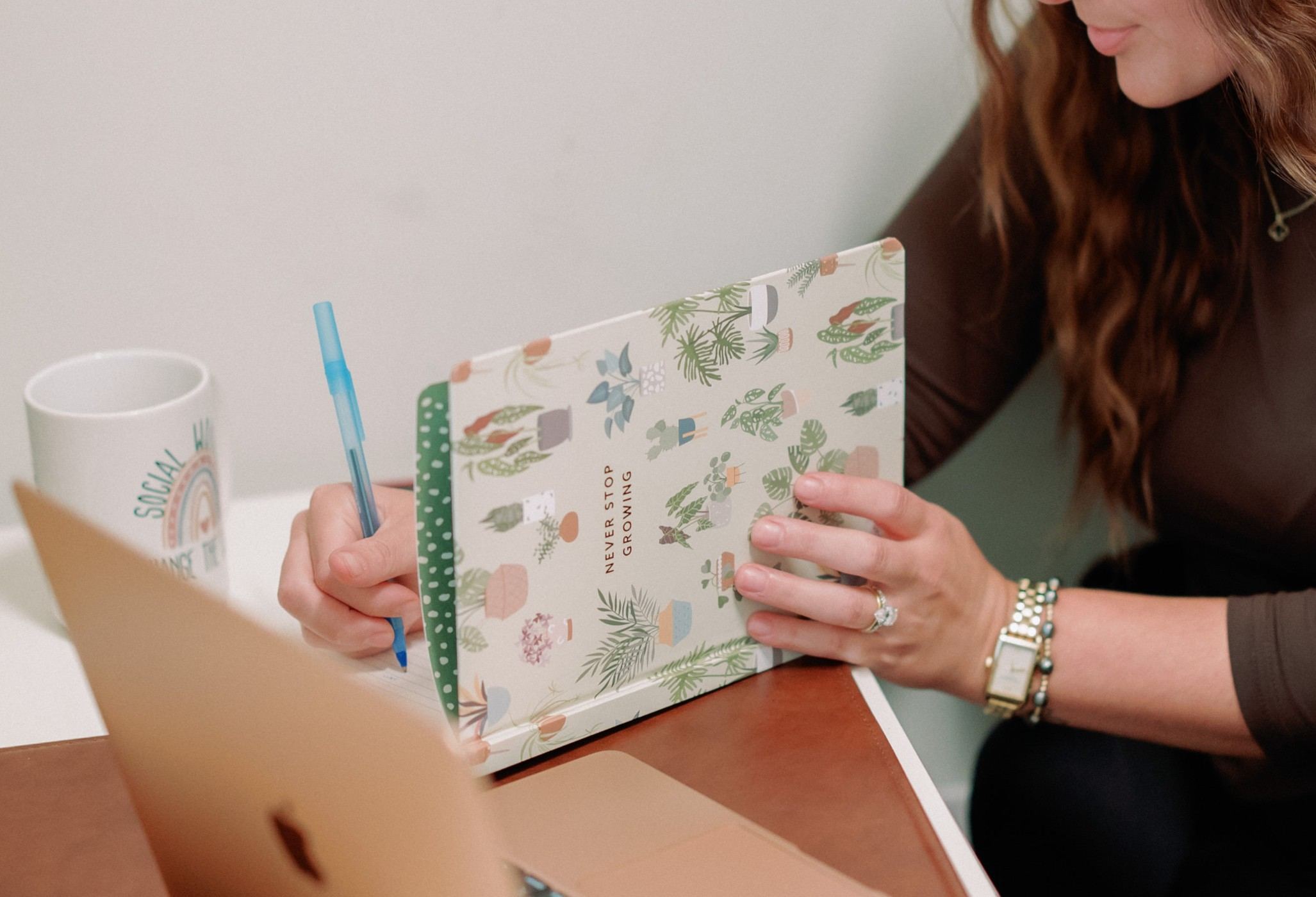 Jennifer Lombardo writing in a notebook that reads 'Never stop growing'
