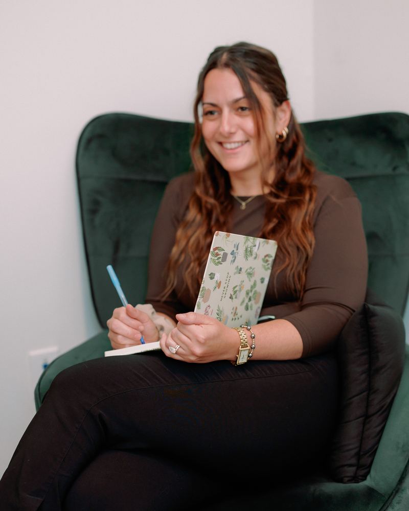 Jennifer Lombardo in a green armchair with a notebook and pen